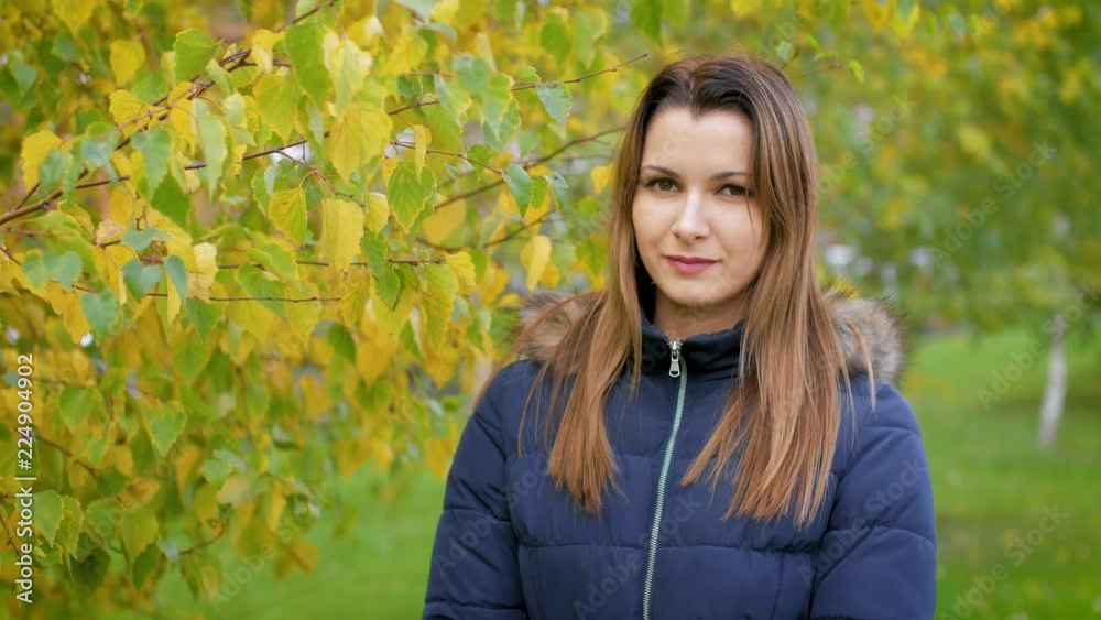 Portrait of happy lovely and beautiful young woman in forest in fall colors. Girl walking in the autumn city Park. 4k