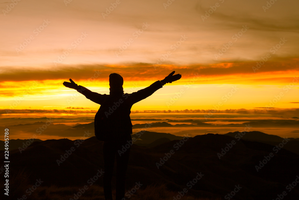 silhouette of female standing on top a mountain with open arms 