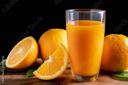 Glass of orange juice with fresh fruits on wooden floor