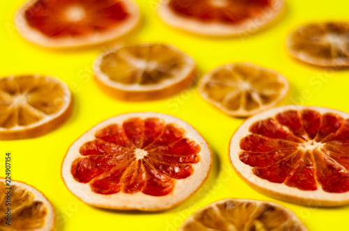 Scattered dried slices grapefruit and lemon on yellow background photo