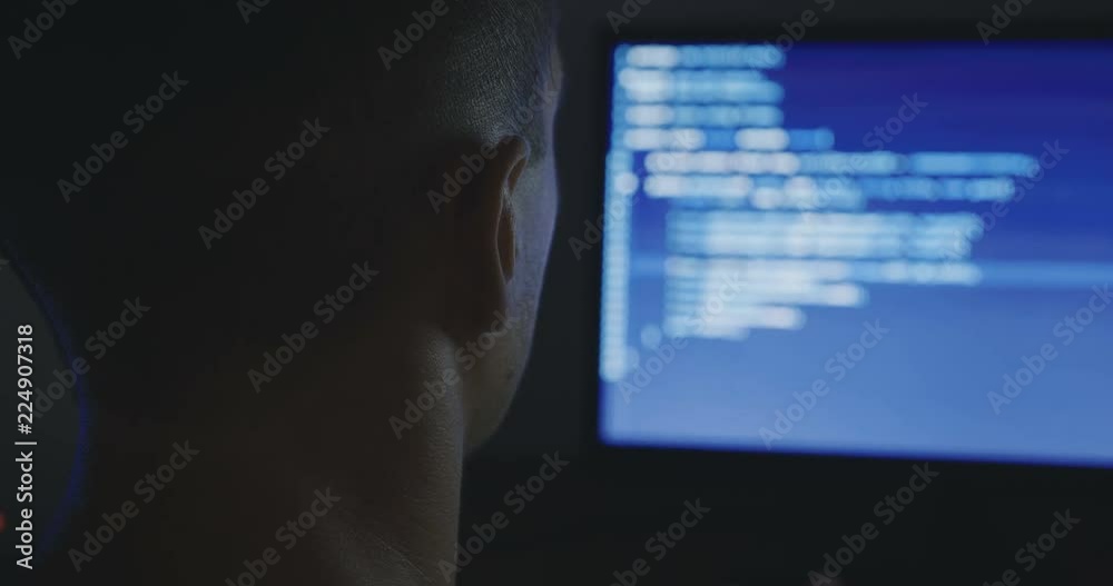 IT Programmer man typing in program code. Developer at work overtime. Hacker hacking late at night. IT Programmer man typing in program code. Developer at work overtime. Hacker hacking late at night.