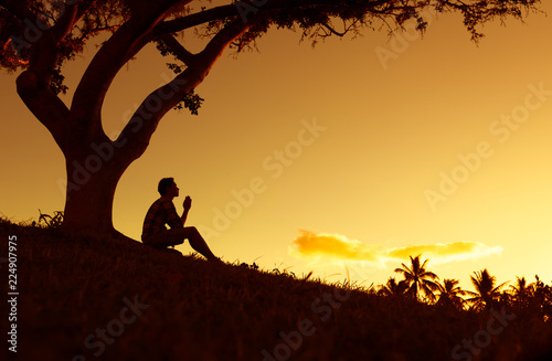 Silhouette of man praying outdoors. 