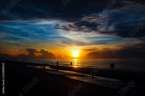 Someone is walking on the on beach while the sunset.