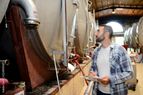 handsome man winemaker in a winery wine cellar during harvest season with stainless steel vats in background