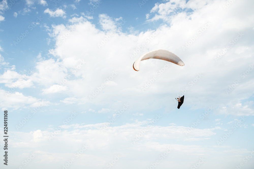 Alone paraglider flying in the blue sky against the background of clouds. Paragliding in the sky on a sunny day Alone paraglider flying in the blue sky against the background of clouds. Paragliding in the sky on a sunny day