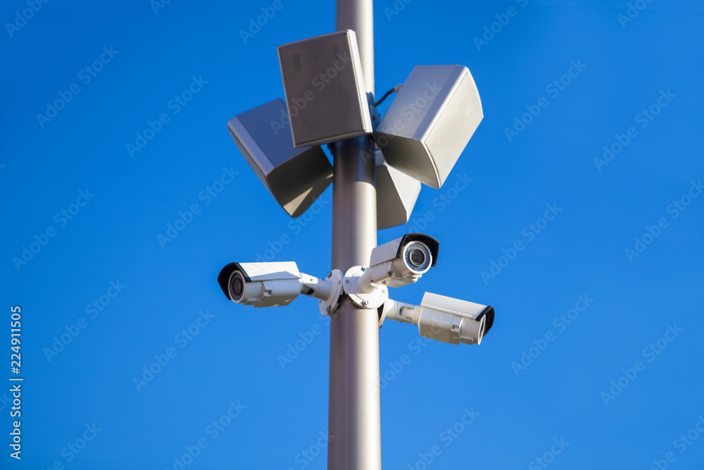 CCTV Security Camera And Loudspeaker Or Speaker With Clear Blue Sky On Background. Security And Protection Of Public Order And Peace. CCTV Security Camera And Loudspeaker Or Speaker With Clear Blue Sky On Background. Security And Protection Of Public Order And Peace.