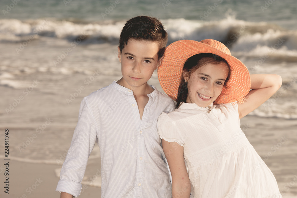 Obraz premium boy and girl on the beach, she with an orange hat