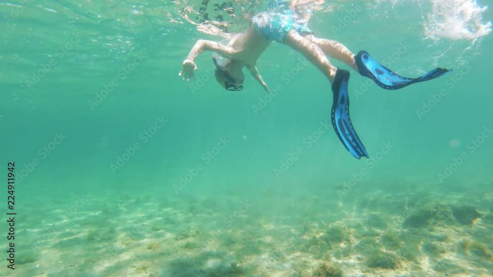 Little boy with flippers, mask and snorkel swimming and diving in the sea, action camera underwater footage Little boy with flippers, mask and snorkel swimming and diving in the sea, action camera underwater footage