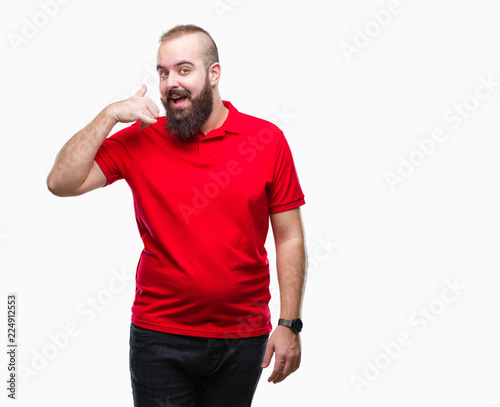 Young caucasian hipster man wearing red shirt over isolated background smiling doing phone gesture with hand and fingers like talking on the telephone. Communicating concepts.