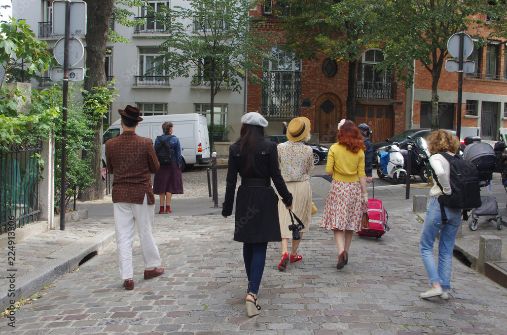 Group of tourists in the cobbled streets of Montmartre in Paris with the house facades in the background Group of tourists in the cobbled streets of Montmartre in Paris with the house facades in the background