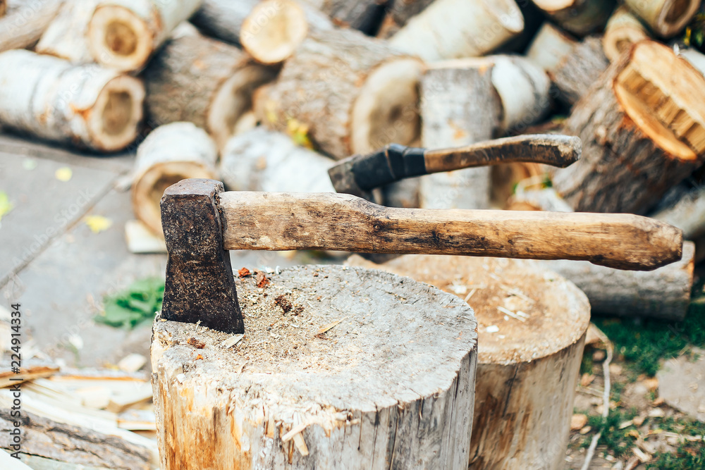 A sharp blade of an ax that sticks out in a wooden chock. rustic concept A sharp blade of an ax that sticks out in a wooden chock. rustic concept