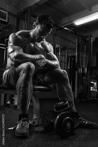 White Muscular man fitness model is resting in the gym and looking down. BW