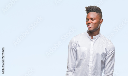 Young african american man over isolated background looking away to side with smile on face, natural expression. Laughing confident.