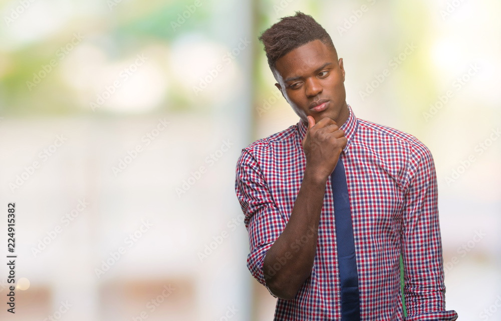 Young african american business man over isolated background with hand on chin thinking about question, pensive expression. Smiling with thoughtful face. Doubt concept.