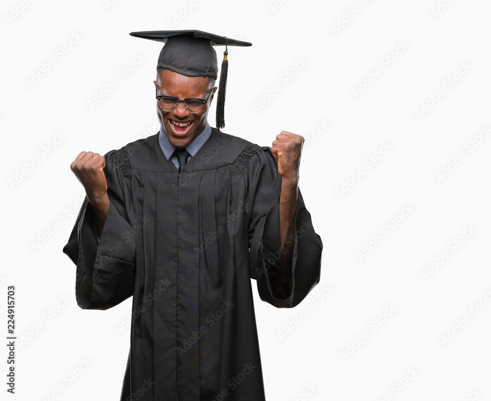 Young graduated african american man over isolated background very happy and excited doing winner gesture with arms raised, smiling and screaming for success. Celebration concept. Young graduated african american man over isolated background very happy and excited doing winner gesture with arms raised, smiling and screaming for success. Celebration concept.