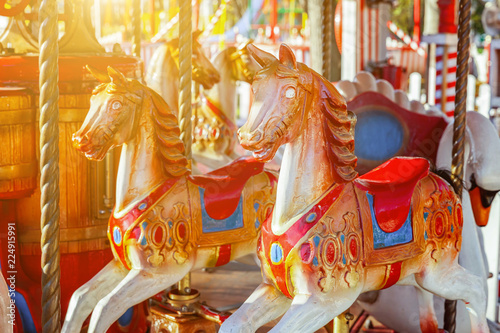 Children outdoor colourful vintage Merry-Go-Round flying horse carousel in amusement holliday park in city. Attraction detail horses and animals with lots gold paintwork on traditional retro carnival photo