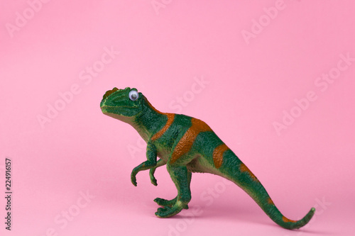 funny green dinosaur toy on pastel pink background