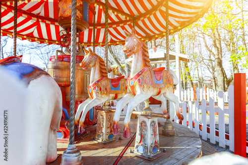 Children outdoor colourful vintage Merry-Go-Round flying horse carousel in amusement holliday park in city. Attraction detail horses and animals with lots gold paintwork on traditional retro carnival photo