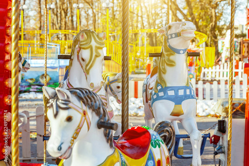 Children outdoor colourful vintage Merry-Go-Round flying horse carousel in amusement holliday park in city. Attraction detail horses and animals with lots gold paintwork on traditional retro carnival