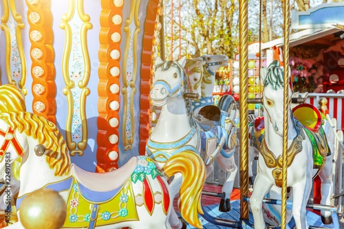 Children outdoor colourful vintage Merry-Go-Round flying horse carousel in amusement holliday park in city. Attraction detail horses and animals with lots gold paintwork on traditional retro carnival photo
