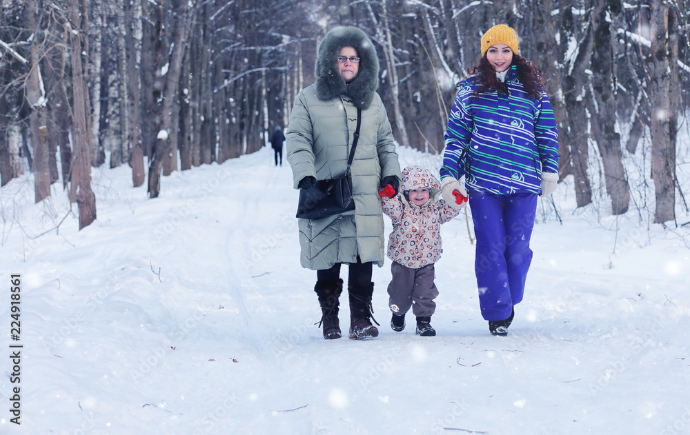 family with kid walk in winter park snowy