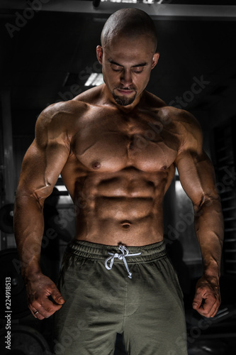 White Muscular man fitness model is posing in the gym and looking down