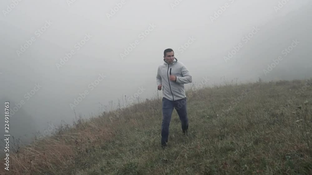 Jogging man athlete on the grass in the fog,slow mo