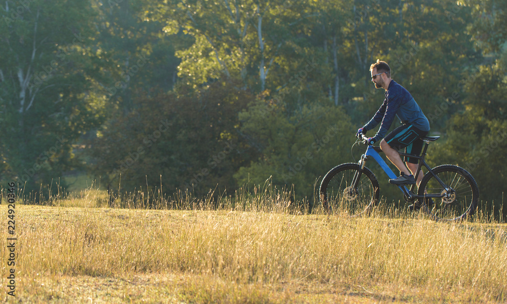 A cyclist rides the hills, Beautiful portrait of a guy on a blue bicycle A cyclist rides the hills, Beautiful portrait of a guy on a blue bicycle