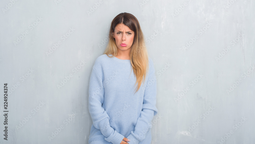 Young adult woman over grey grunge wall wearing winter outfit depressed and worry for distress, crying angry and afraid. Sad expression. Young adult woman over grey grunge wall wearing winter outfit depressed and worry for distress, crying angry and afraid. Sad expression.