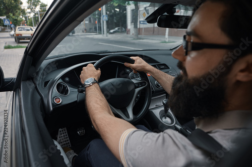 Modern casual bearded man driving a car