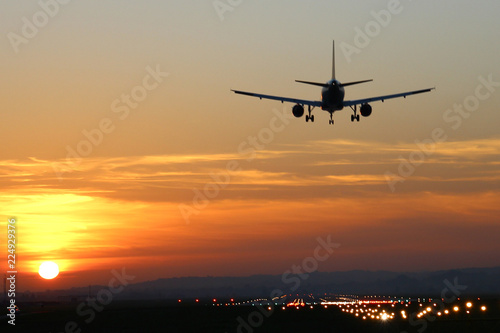 Plane landing at runway on the background of sunset