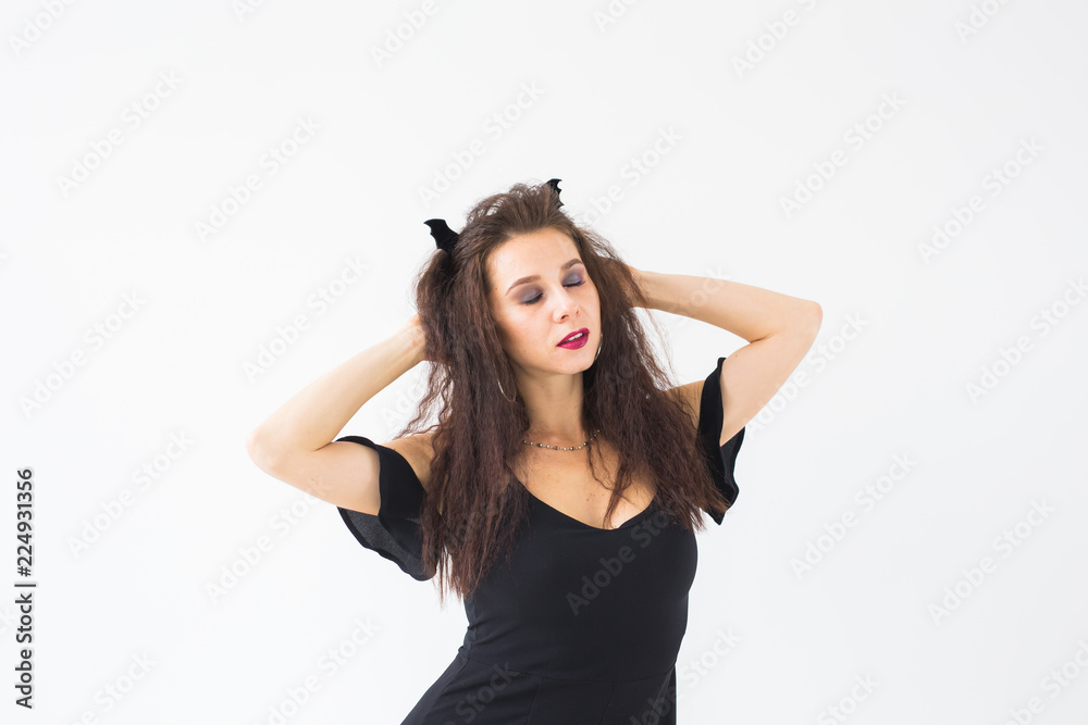 Happy gothic young woman in witch halloween costume smiling over white room background Happy gothic young woman in witch halloween costume smiling over white room background