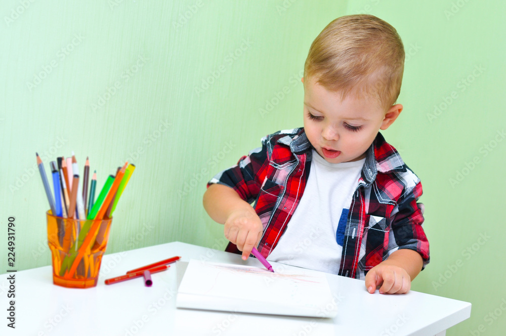 Cute little boy in a red checkered shirt smiles and draws a lilac marker in a white album
Cute little boy in a red checkered shirt smiles and draws a lilac marker in a white album