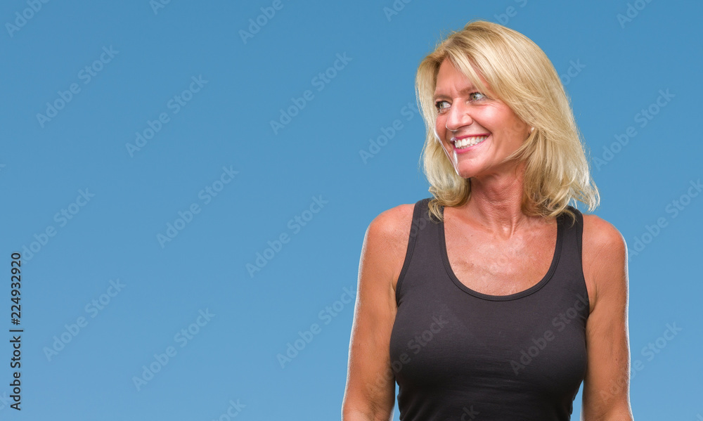 Middle age blonde woman over isolated background looking away to side with smile on face, natural expression. Laughing confident. Middle age blonde woman over isolated background looking away to side with smile on face, natural expression. Laughing confident.