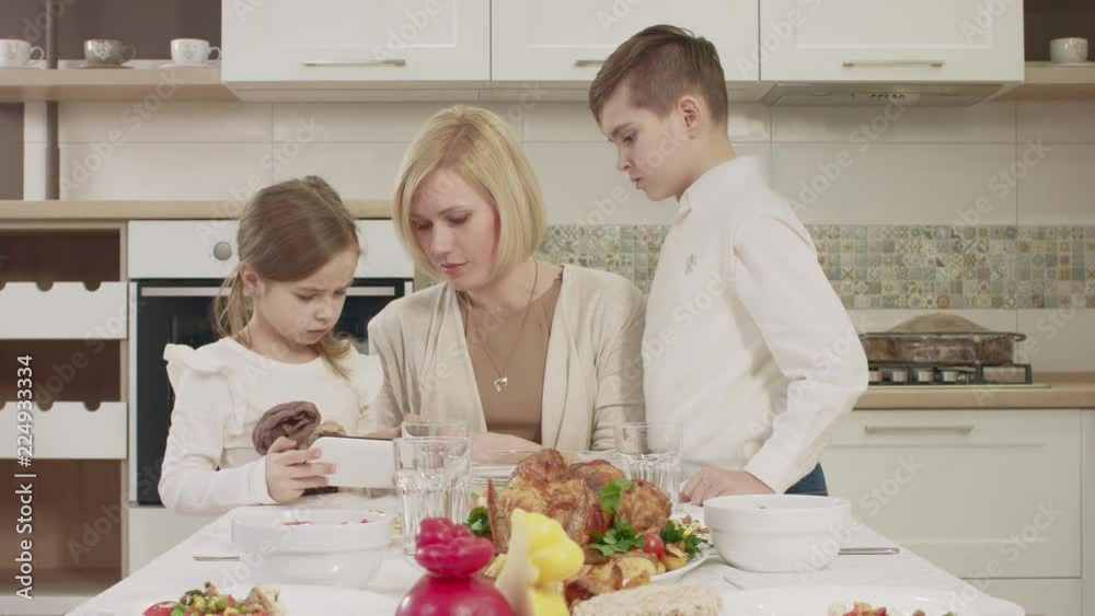 Mom Communicates With Her Children At The Table During A Family Dinner Mom Communicates With Her Children At The Table During A Family Dinner