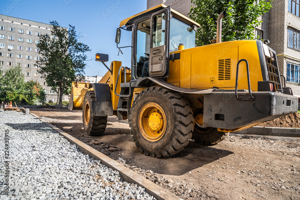 yellow loader with empty bucket is standing at construction site