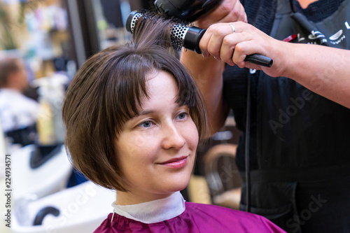 Beautiful young woman in hairstyle salon getting bob haircut