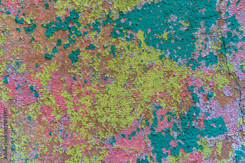 an old painted wall with pealing paint, yellow, blue, pink spots