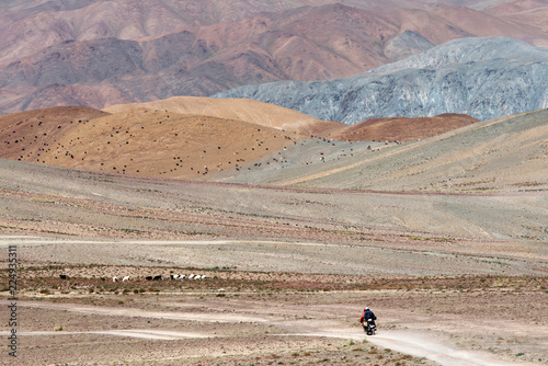 Mongolian landscape with a unknown local biker driving on gravel road to Gobi desert