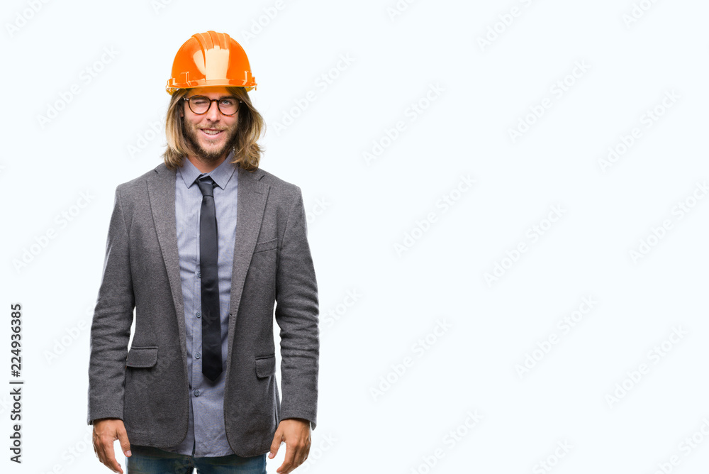 Young handsome architec man with long hair wearing safety helmet over isolated background winking looking at the camera with sexy expression, cheerful and happy face. Young handsome architec man with long hair wearing safety helmet over isolated background winking looking at the camera with sexy expression, cheerful and happy face.