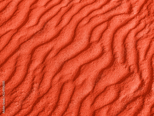 texture of red sand waves on the beach or in the desert. the ripples of the sand is diagonal.