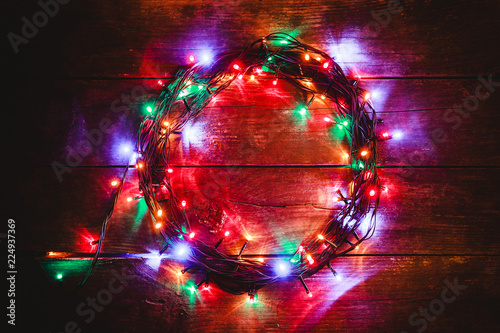 Wooden background with bright colored lights. In the center is space for the message. Top view.