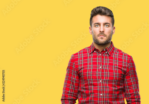 Young handsome man over isolated background with serious expression on face. Simple and natural looking at the camera.