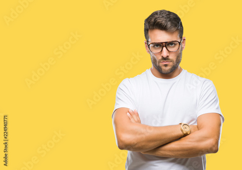 Young handsome man wearing glasses over isolated background skeptic and nervous, disapproving expression on face with crossed arms. Negative person.