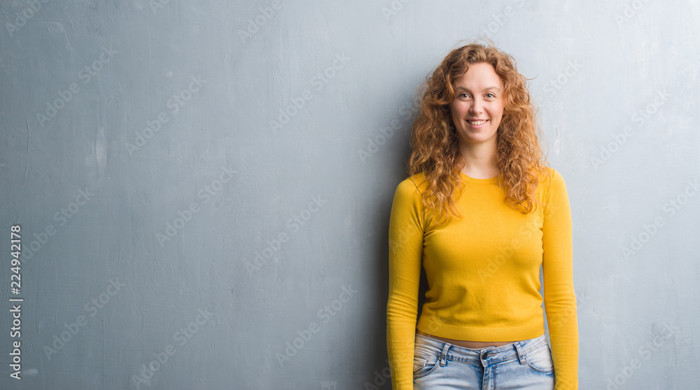 Young redhead woman over grey grunge wall with a happy and cool smile on face. Lucky person. Young redhead woman over grey grunge wall with a happy and cool smile on face. Lucky person.