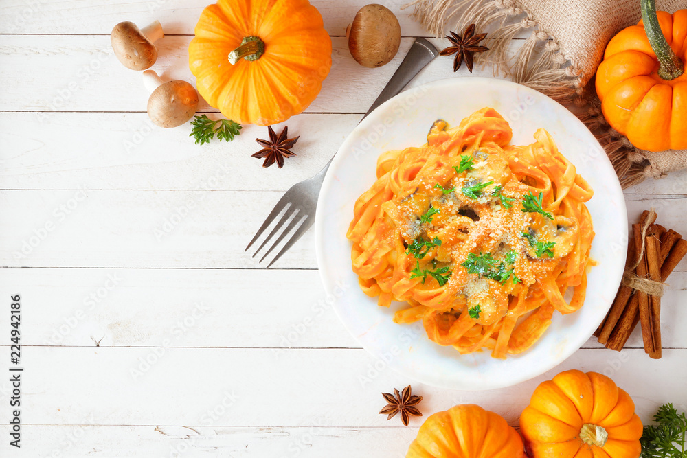 Pasta with a pumpkin, mushroom cream sauce. Autumn meal. Top view scene on a white wood background with copy space.