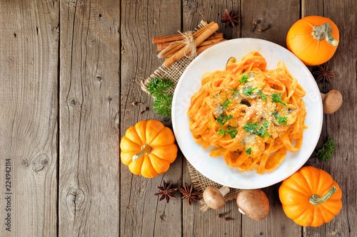 Pasta with a pumpkin, mushroom cream sauce. Autumn meal. Top view scene on a wood background.