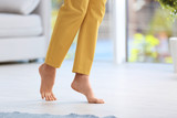 Woman walking barefoot at home, space for text. Floor heating