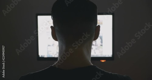 Back view of Young Man secretly watching porn sites at night.