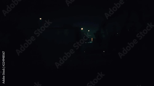 Passenger train passing slowly through the city at night. Outside view from the window.